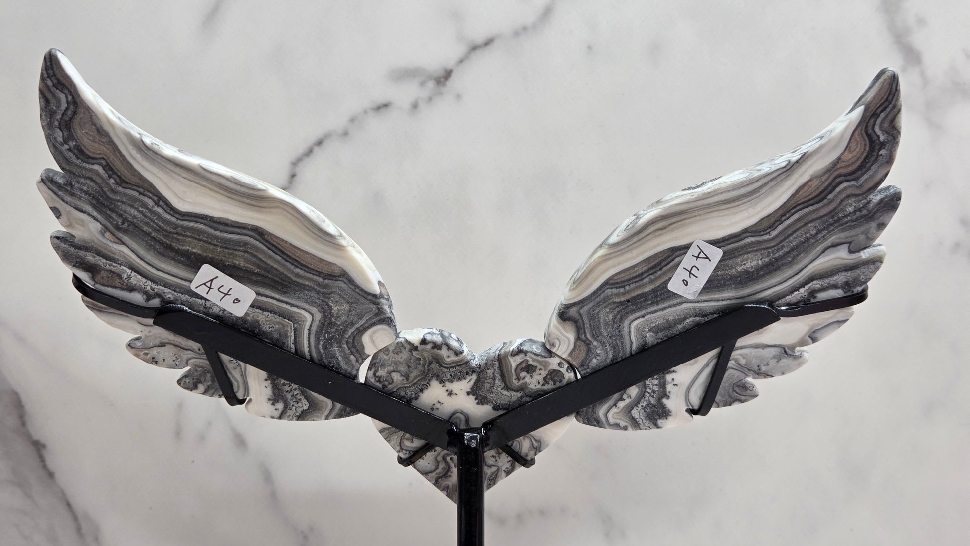 Decorative Zebra Calcite heart with wings, on a stand. Black and white banding and marble like patterns