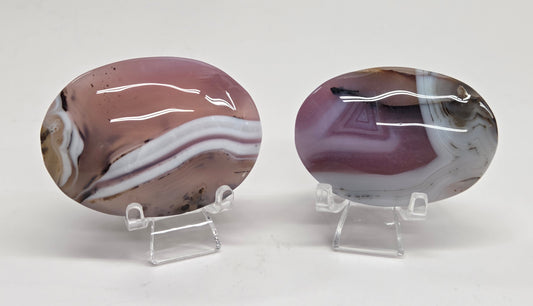 Two marbled stone specimens on clear stands against a white background