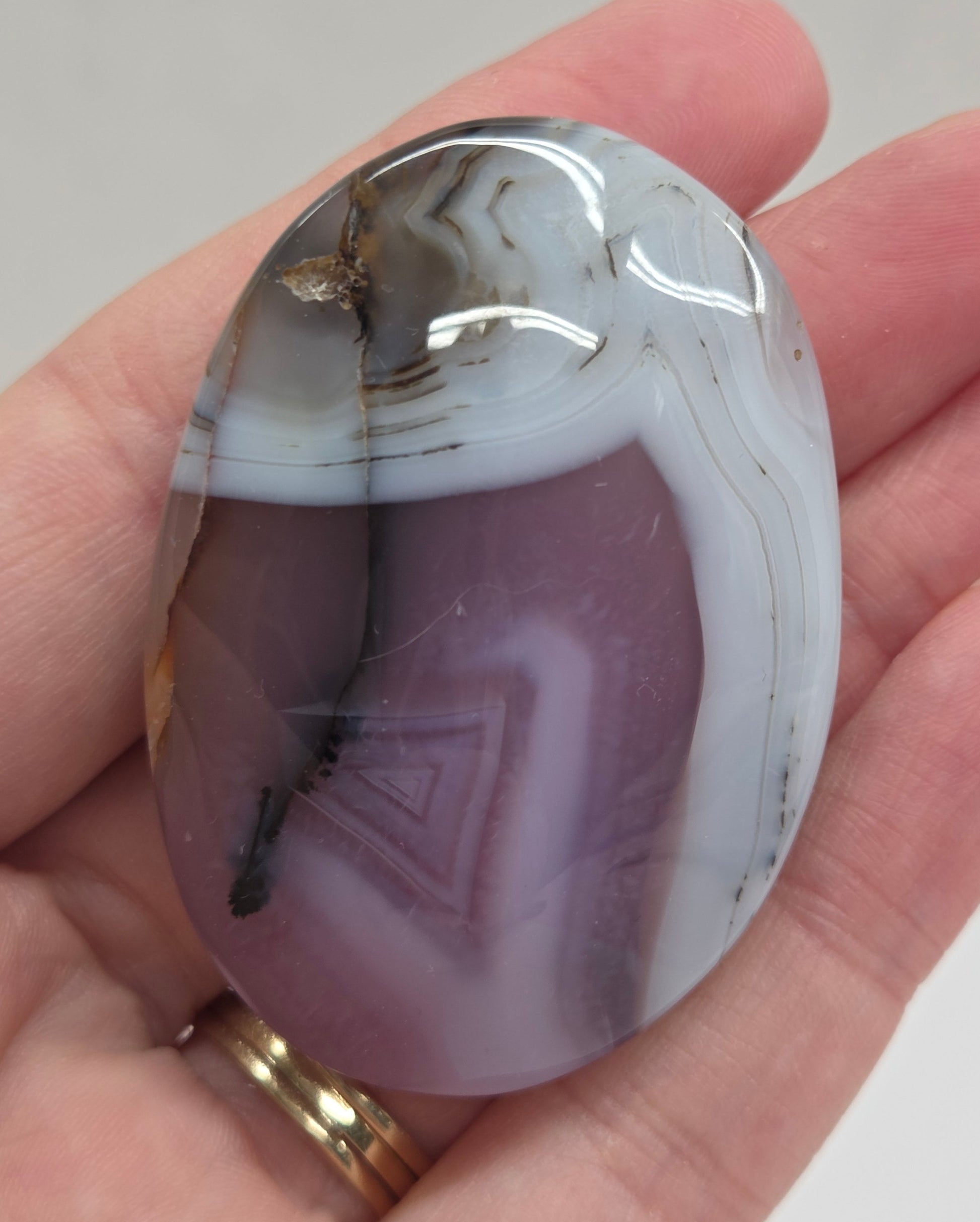 Hand holding a polished Jelly Agate palm with a marbled pattern