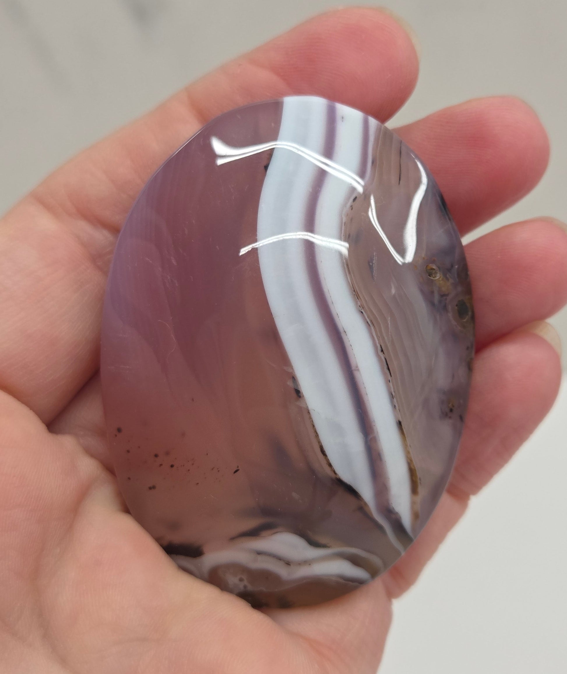 Hand holding a polished Jelly Agate palm with a marbled pattern