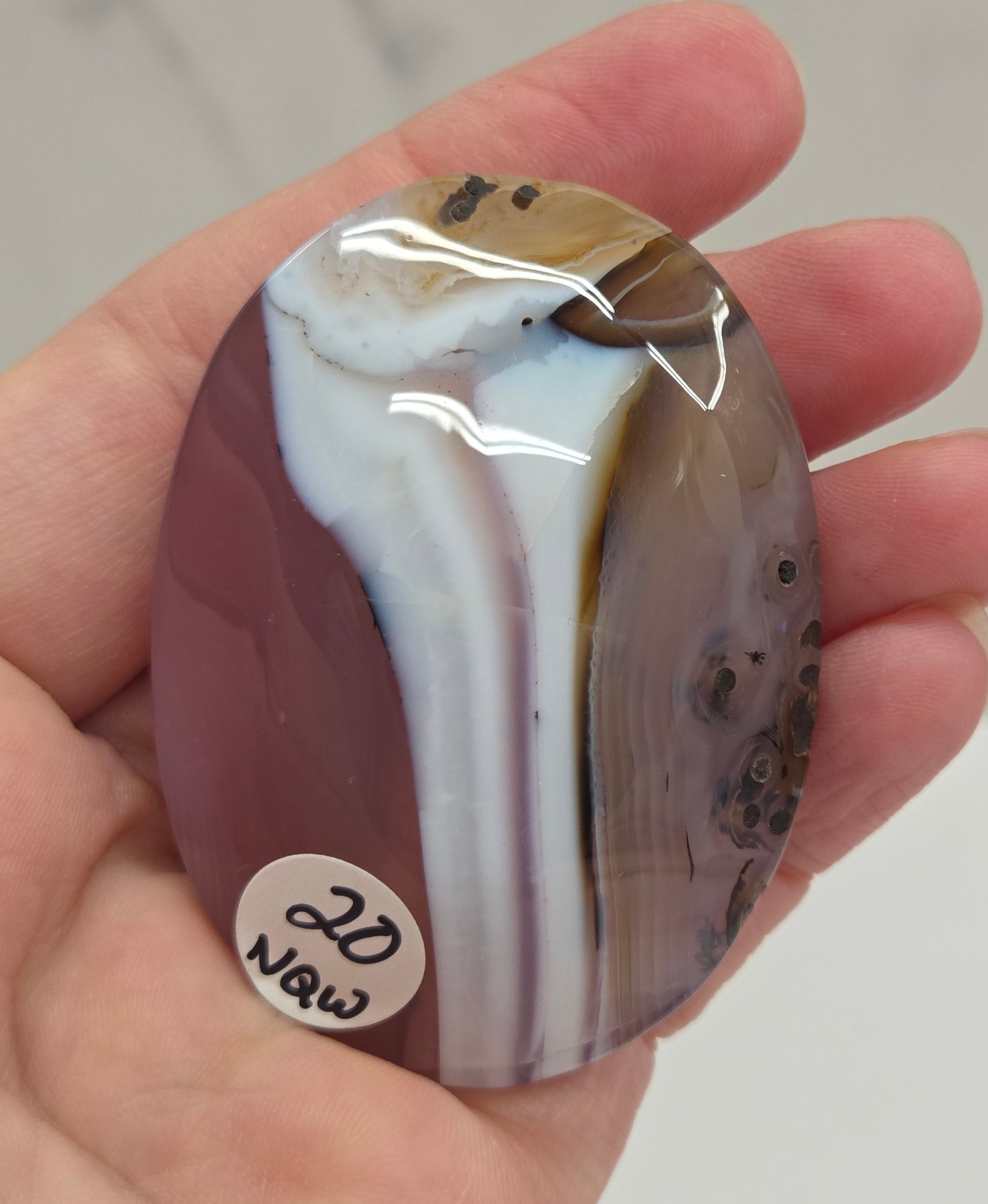 Hand holding a polished Jelly Agate palm with a marbled pattern