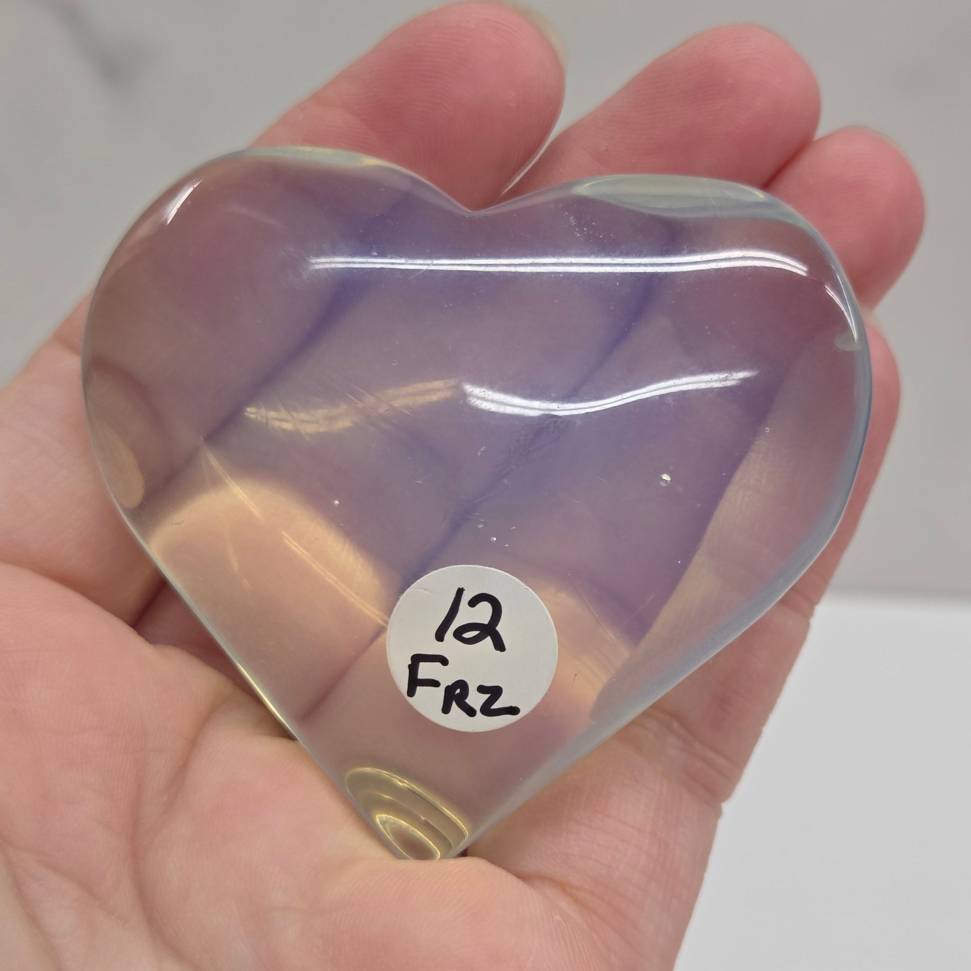 Heart-shaped object with a gradient of purple and yellow held in a hand against a neutral background