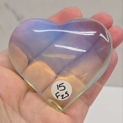 Heart-shaped object with a gradient of purple and yellow held in a hand against a neutral background