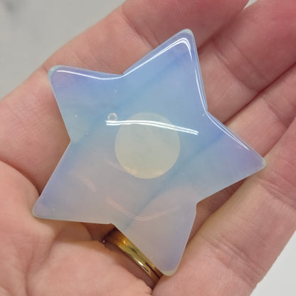 Star-shaped object with a gradient of purple and yellow held in a hand against a neutral background