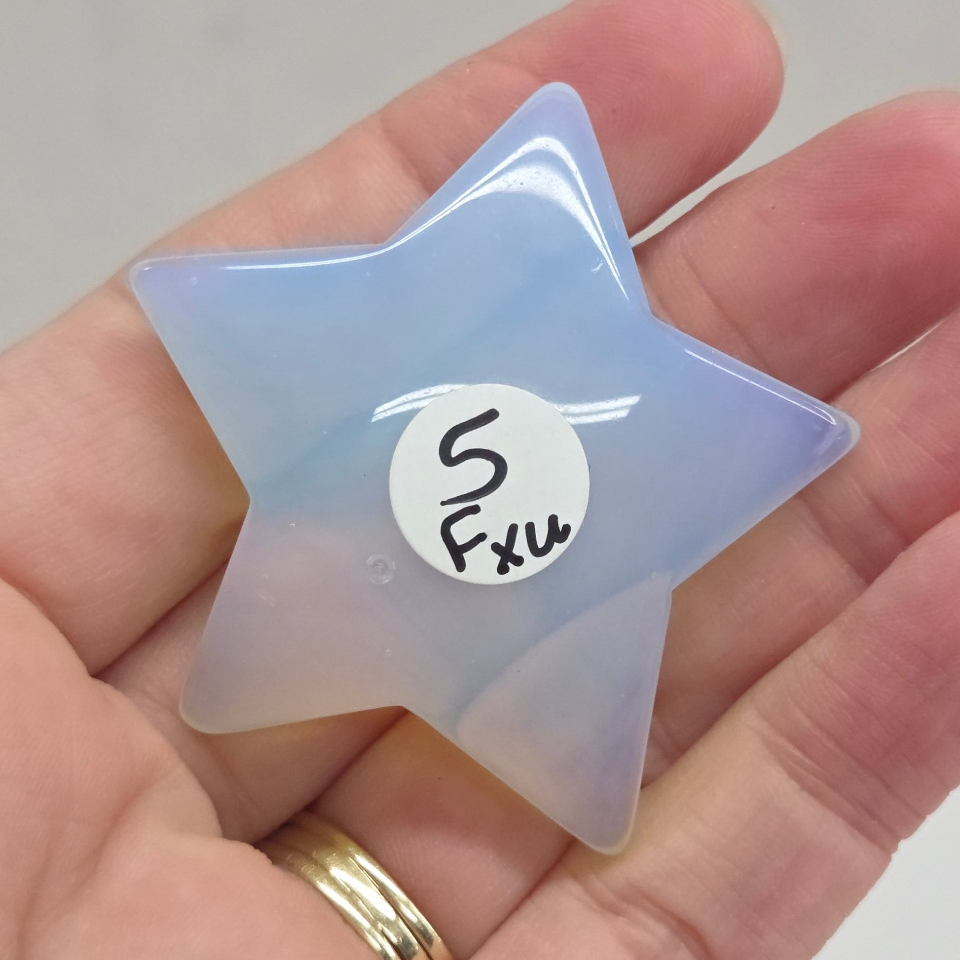 Star-shaped object with a gradient of purple and yellow held in a hand against a neutral background