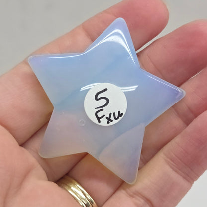 Star-shaped object with a gradient of purple and yellow held in a hand against a neutral background