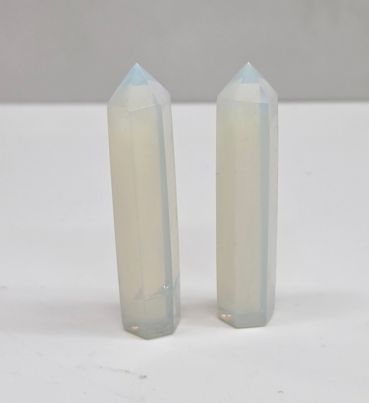 Two crystal points on a white surface with a neutral background