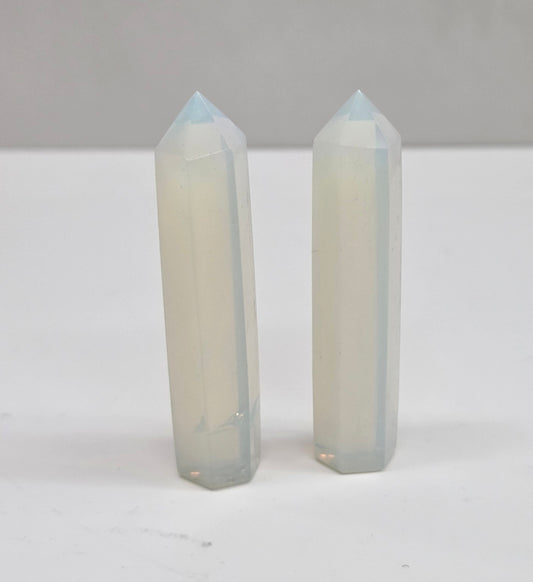 Two crystal points on a white surface with a neutral background