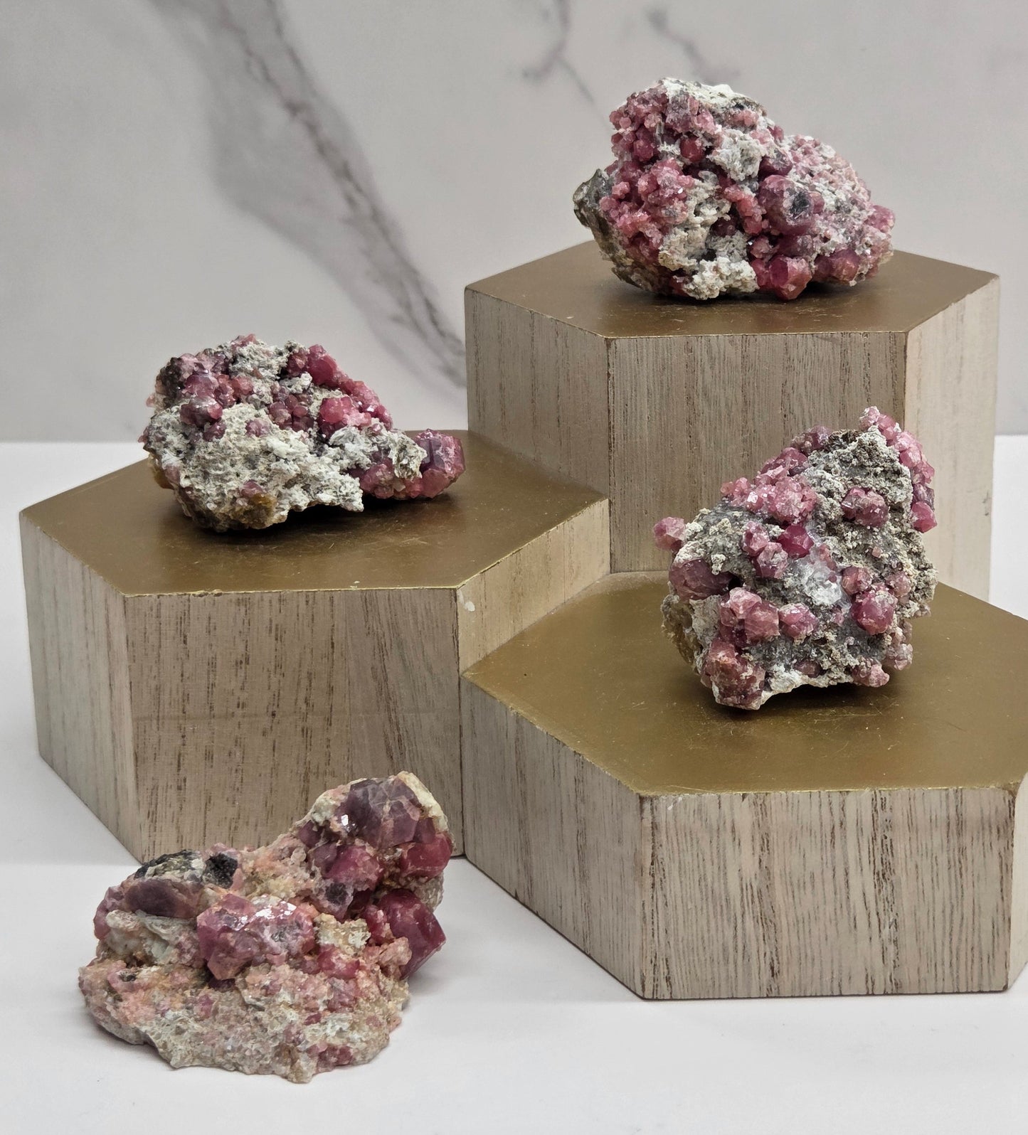 Wooden hexagonal shelf with decorative pink and white Garnet stones on a marble surface