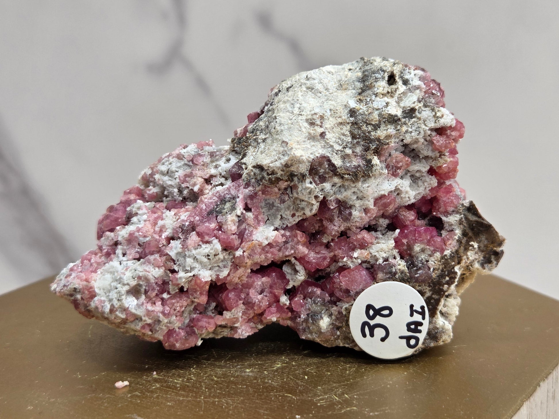 Mineral sample with a label on a wooden stand against a neutral background