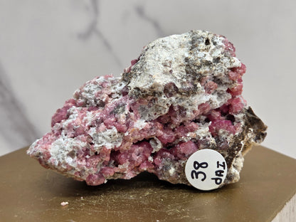 Mineral sample with a label on a wooden stand against a neutral background