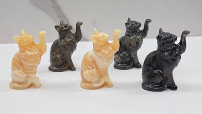Set of five cat-shaped crystal carvings on a white surface with a marble-patterned wall in the background.