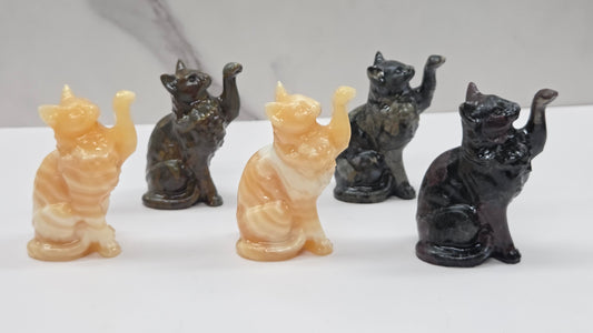 Set of five cat-shaped crystal carvings on a white surface with a marble-patterned wall in the background.