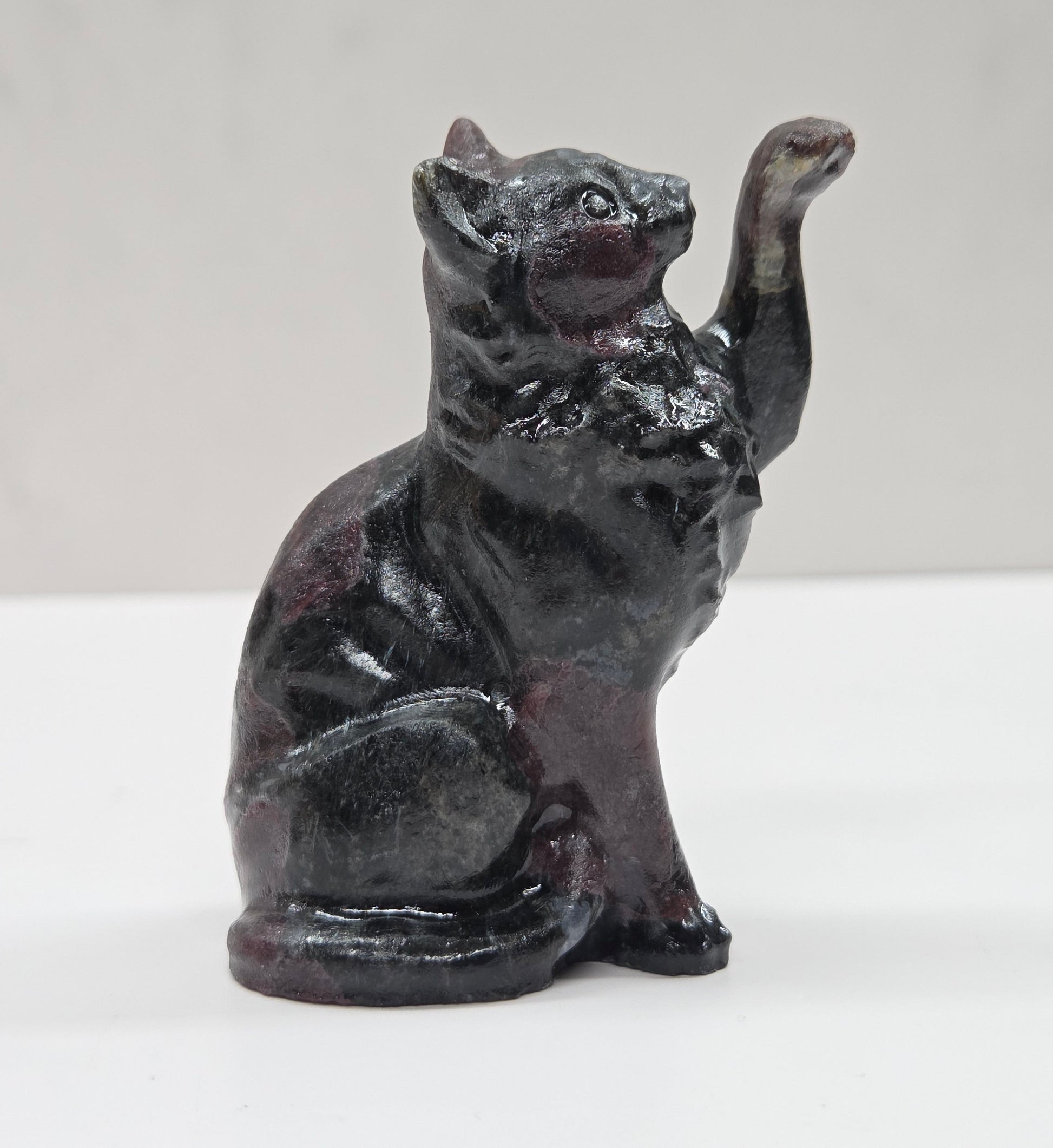 Black cat crystal figurine made of Garnet on a white surface with a light gray background