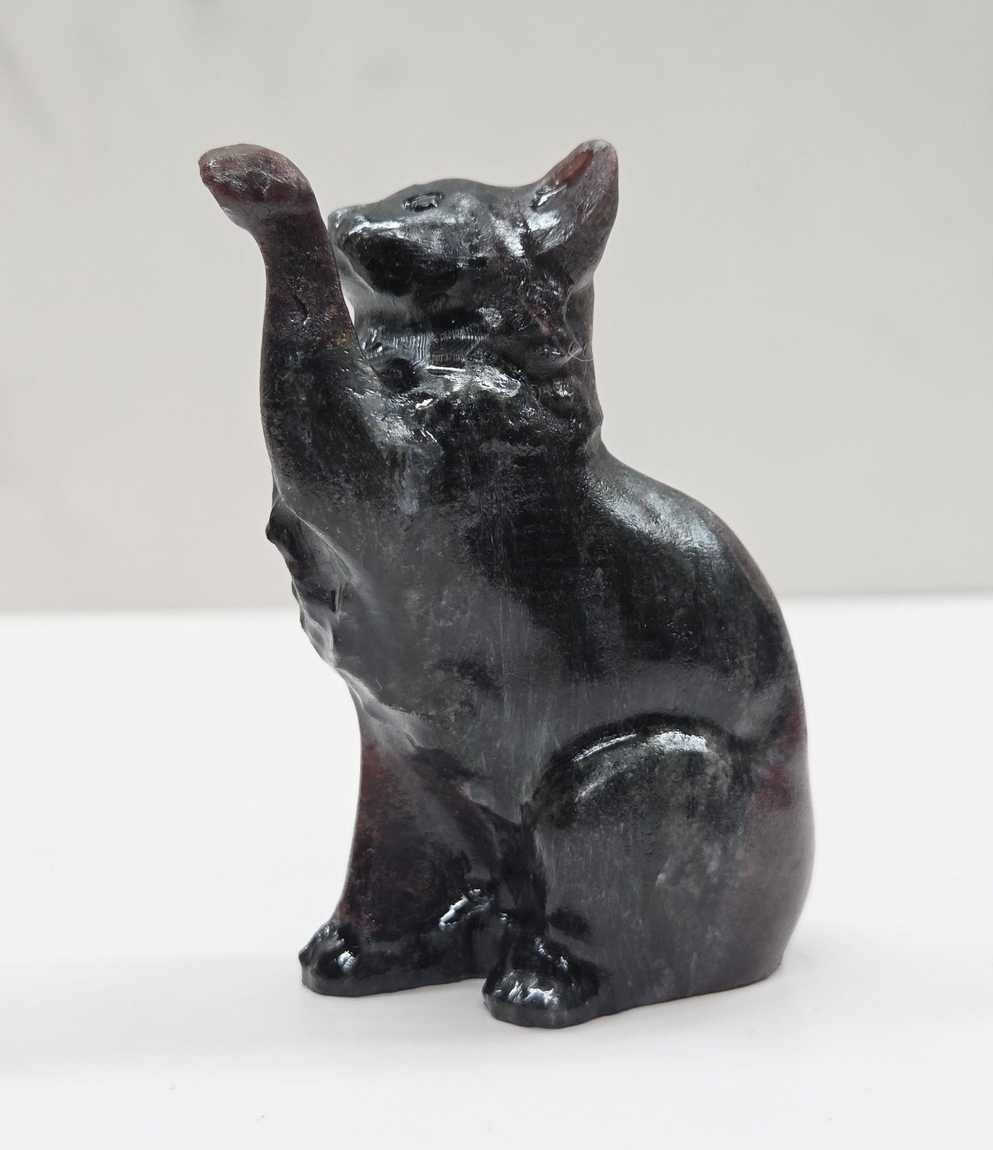 Black cat crystal figurine made of Garnet on a white surface with a light gray background
