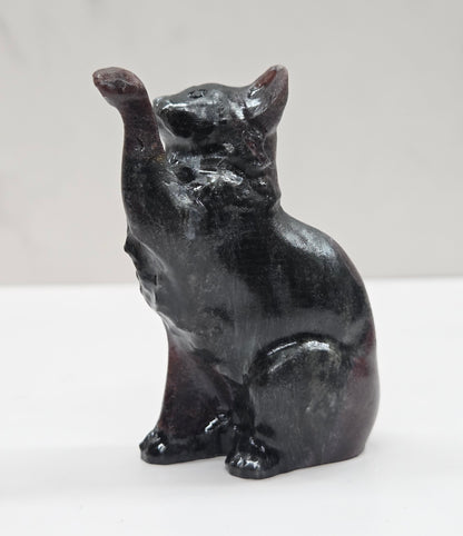 Black cat crystal figurine made of Garnet on a white surface with a light gray background