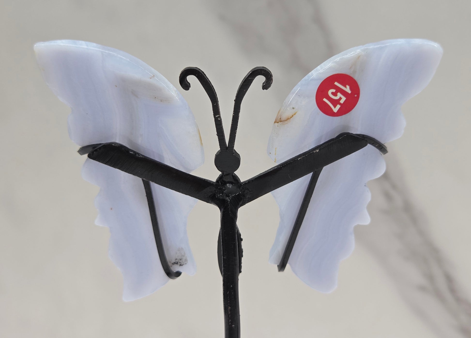 Butterfly-shaped object with white wings and a red label on a gray background