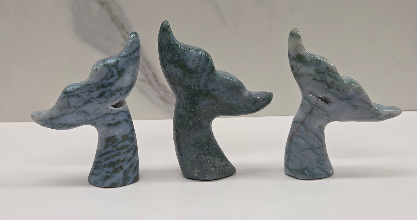 Three stone carvings of stylized whale tales, green, blues and greys and drusy crystal caves