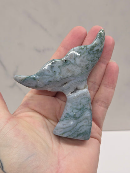 stone carvings of stylized whale tales, green, blues and greys and drusy crystal caves