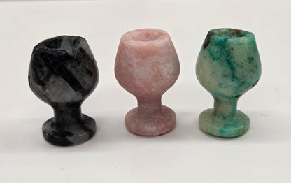 Three stone goblets in black, pink, and green on a white background