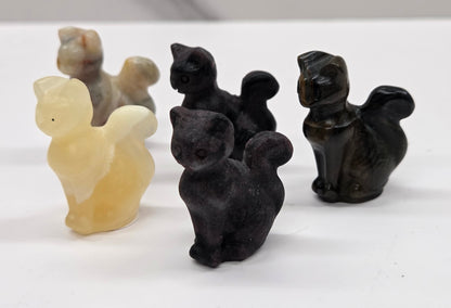 Set of black and beige cat-shaped carvings on a white surface
