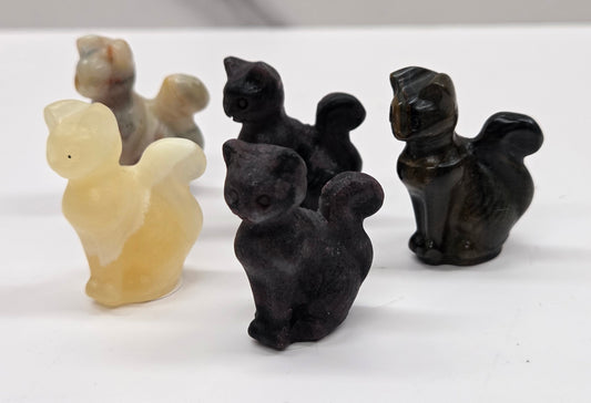 Set of black and beige cat-shaped carvings on a white surface