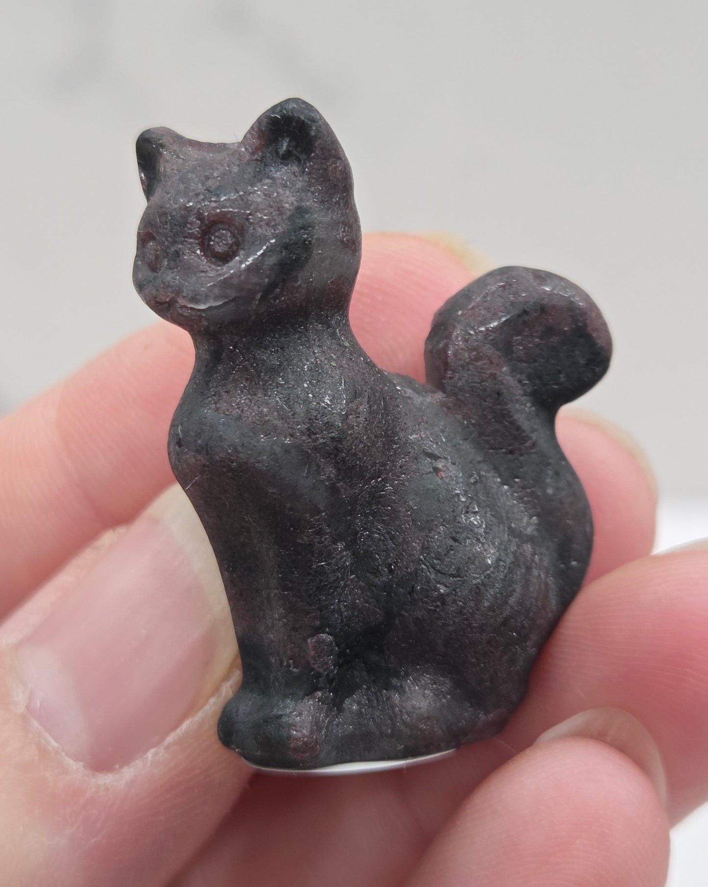 Small black Garnet cat figurine held in a hand against a light background
