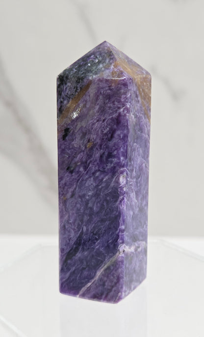 Purple Charoite crystal tower on a light gray background