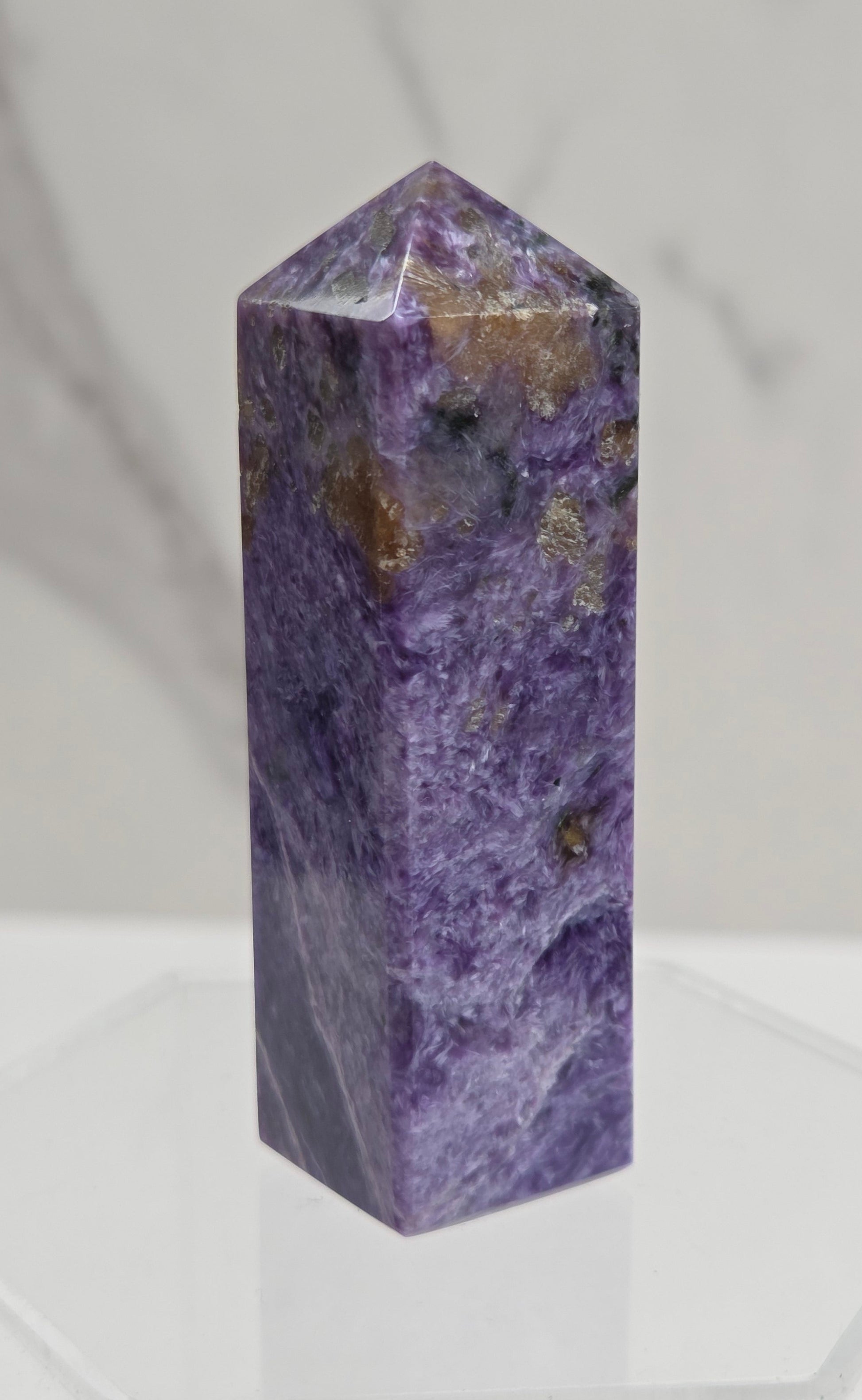 Purple Charoite crystal tower on a light gray background
