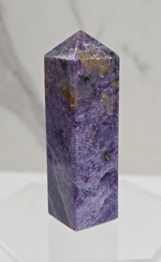 Purple Charoite crystal tower on a light gray background