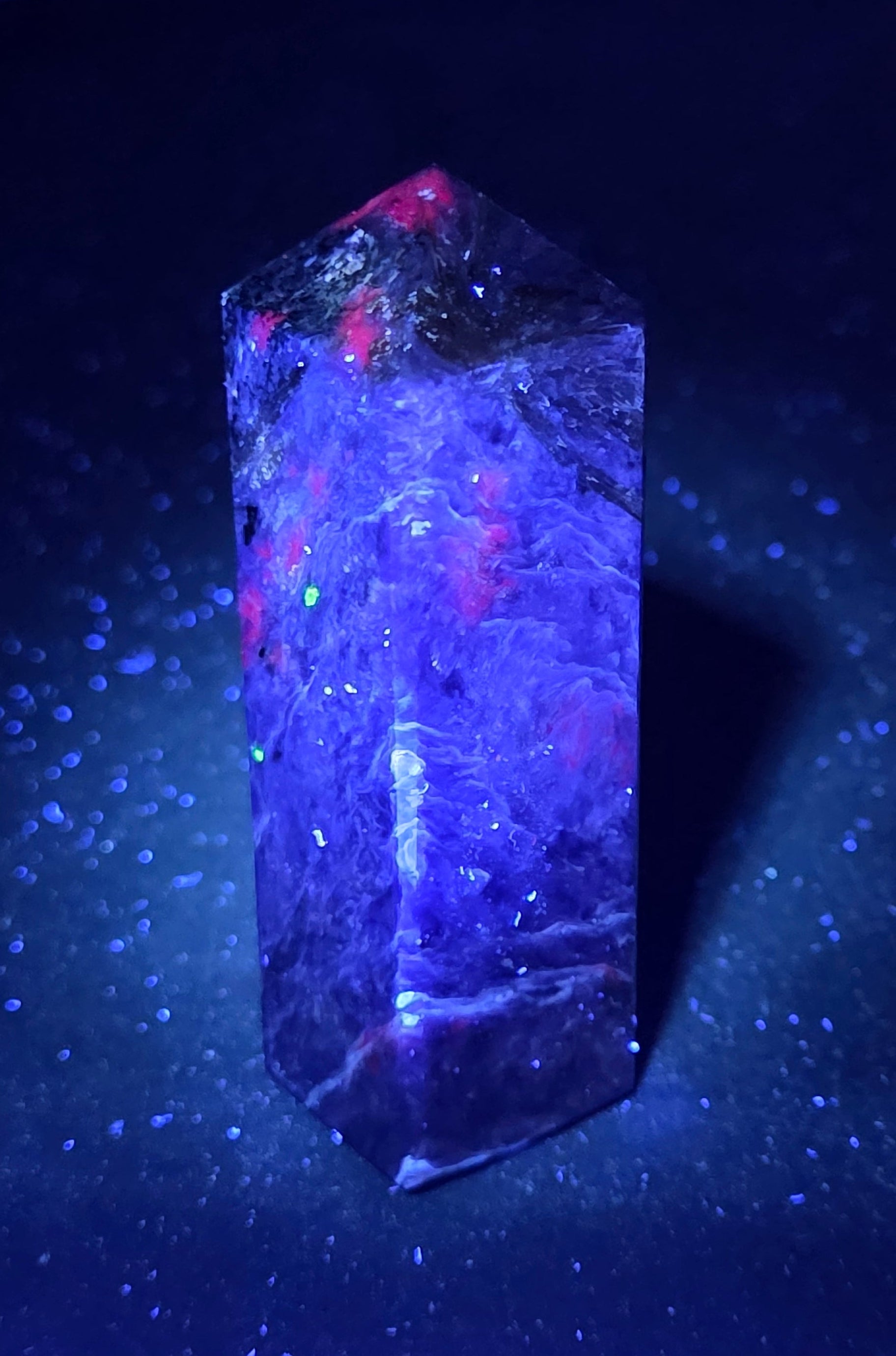 Purple Charoite crystal tower under UV light