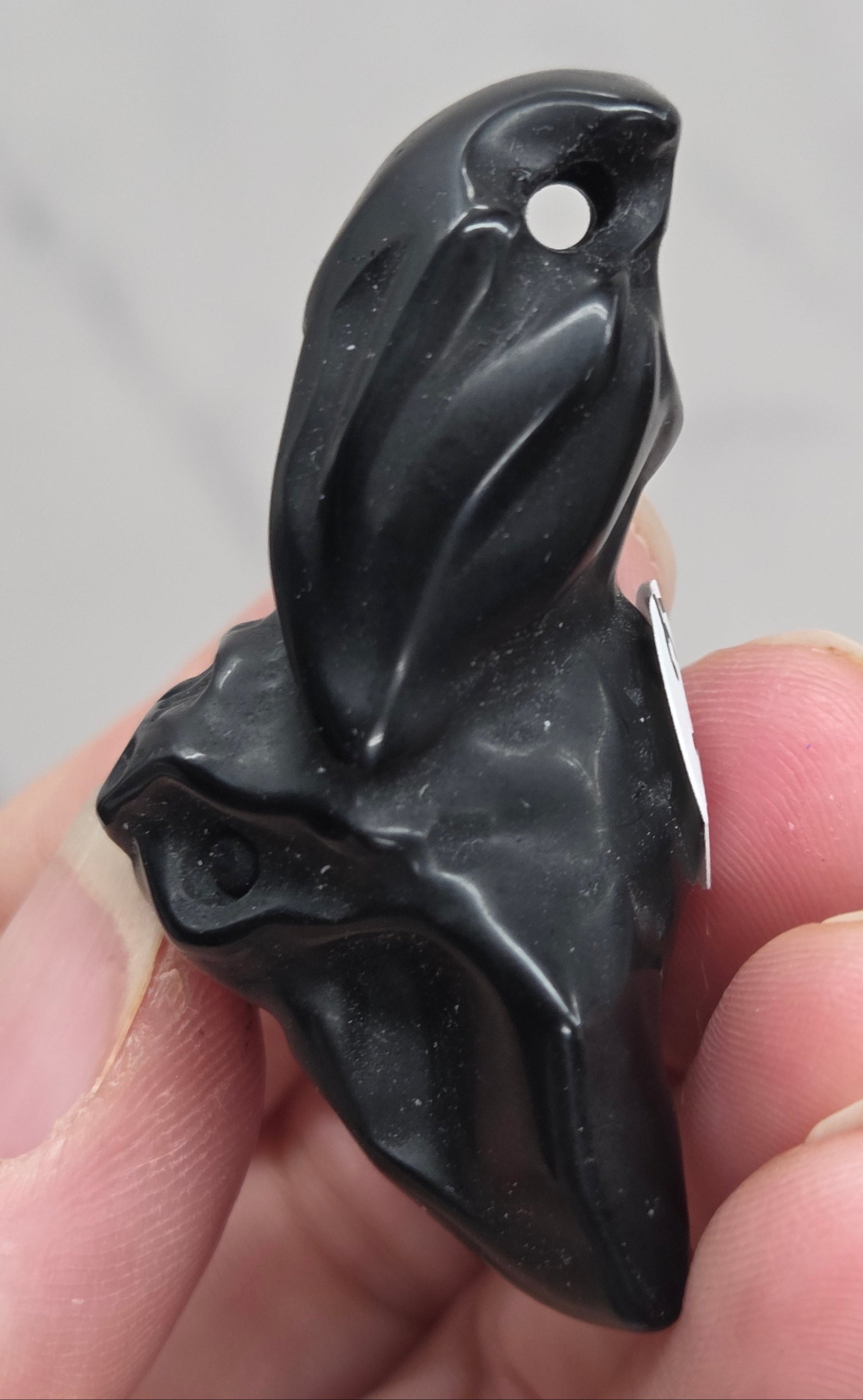 Side view of black Obsidian bat carving showing drilled hole