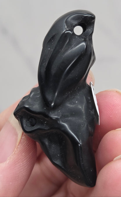 Side view of black Obsidian bat carving showing drilled hole