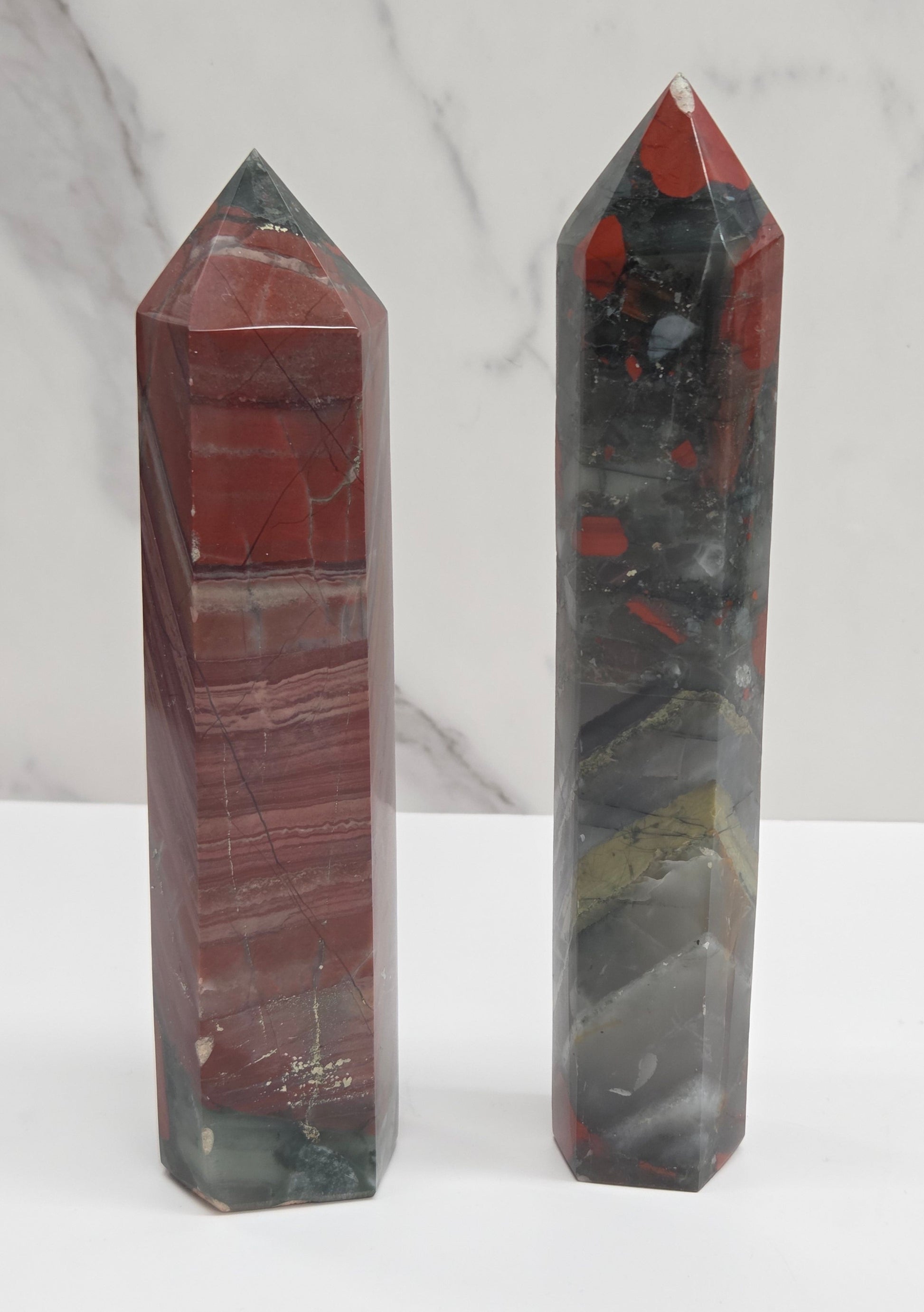 Two crystal African Bloodstone towers with red and black patterns on a white surface