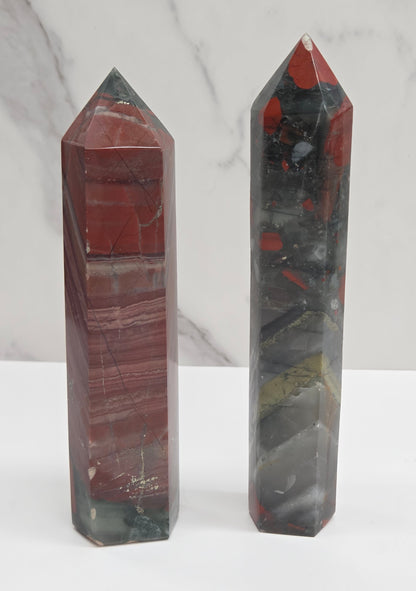 Two crystal African Bloodstone towers with red and black patterns on a white surface