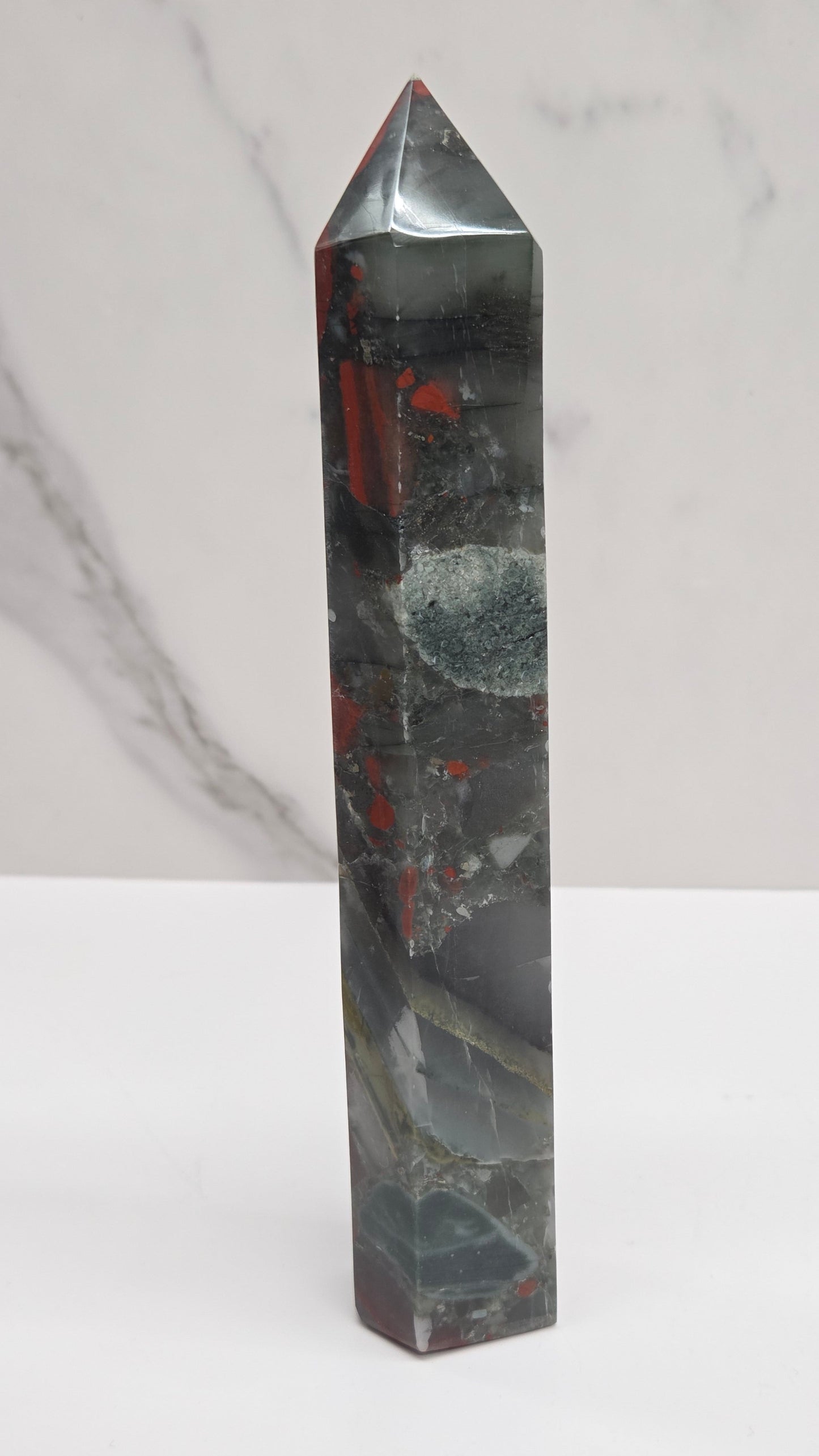 Crystal African Bloodstone tower with red and black patterns on a white surface