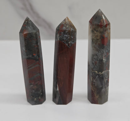 Three polished crystal points made of African Bloodstone on a white background