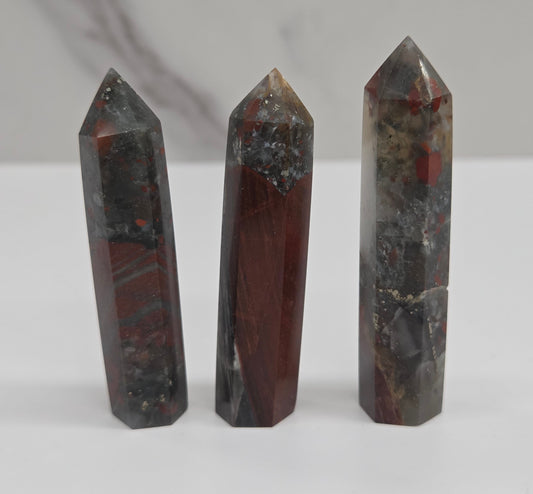 Three polished crystal points made of African Bloodstone on a white background