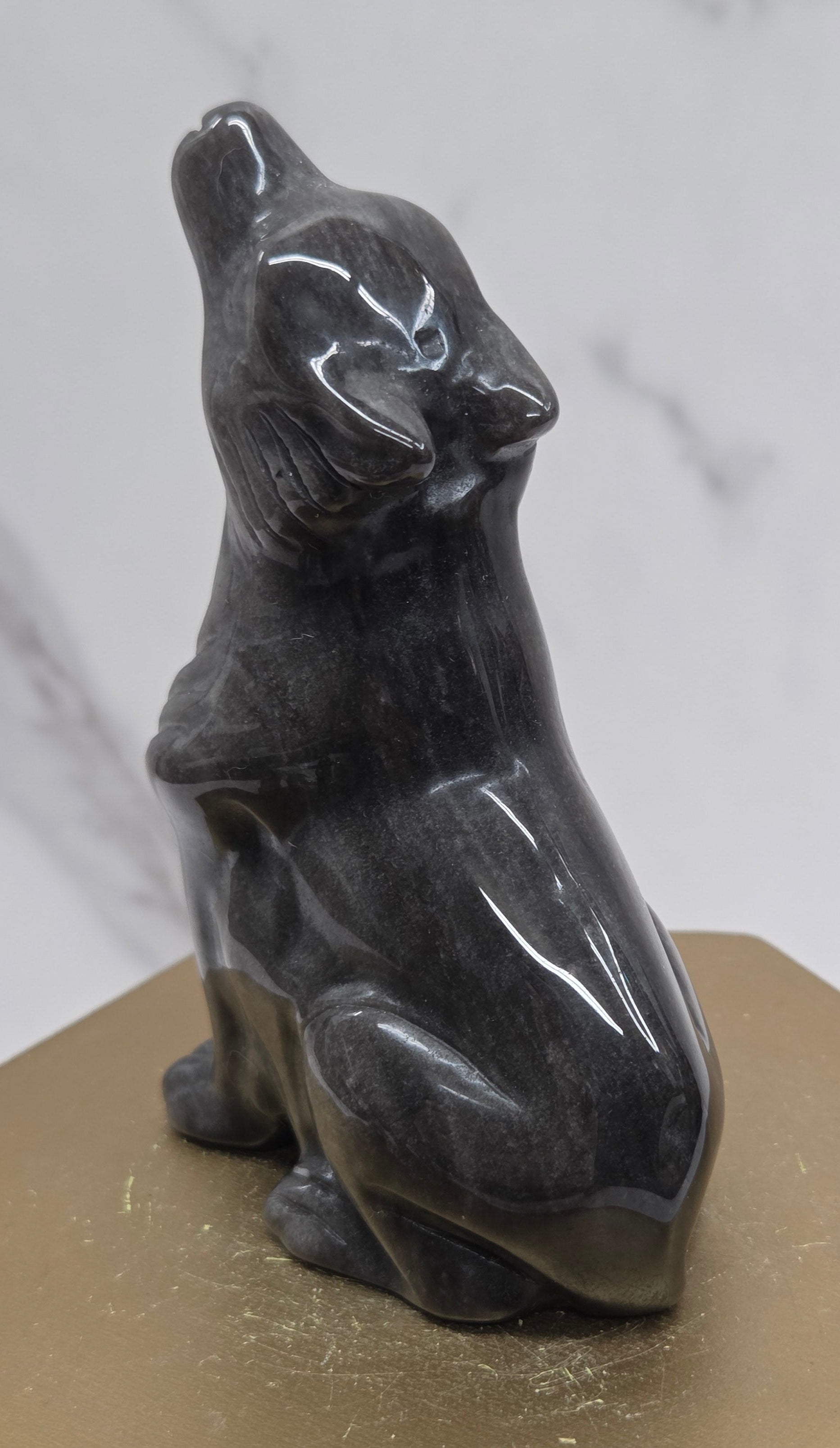 Silver sheen obsidian wolf carving on a neutral background
