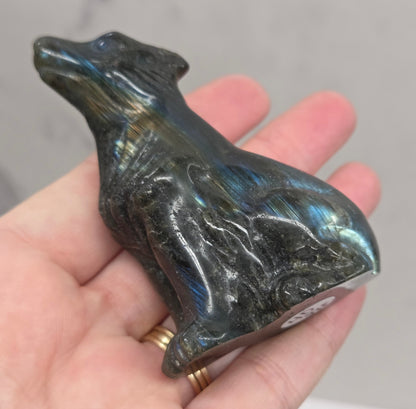 Hand holding a labradorite wolf carving with colorful sheen