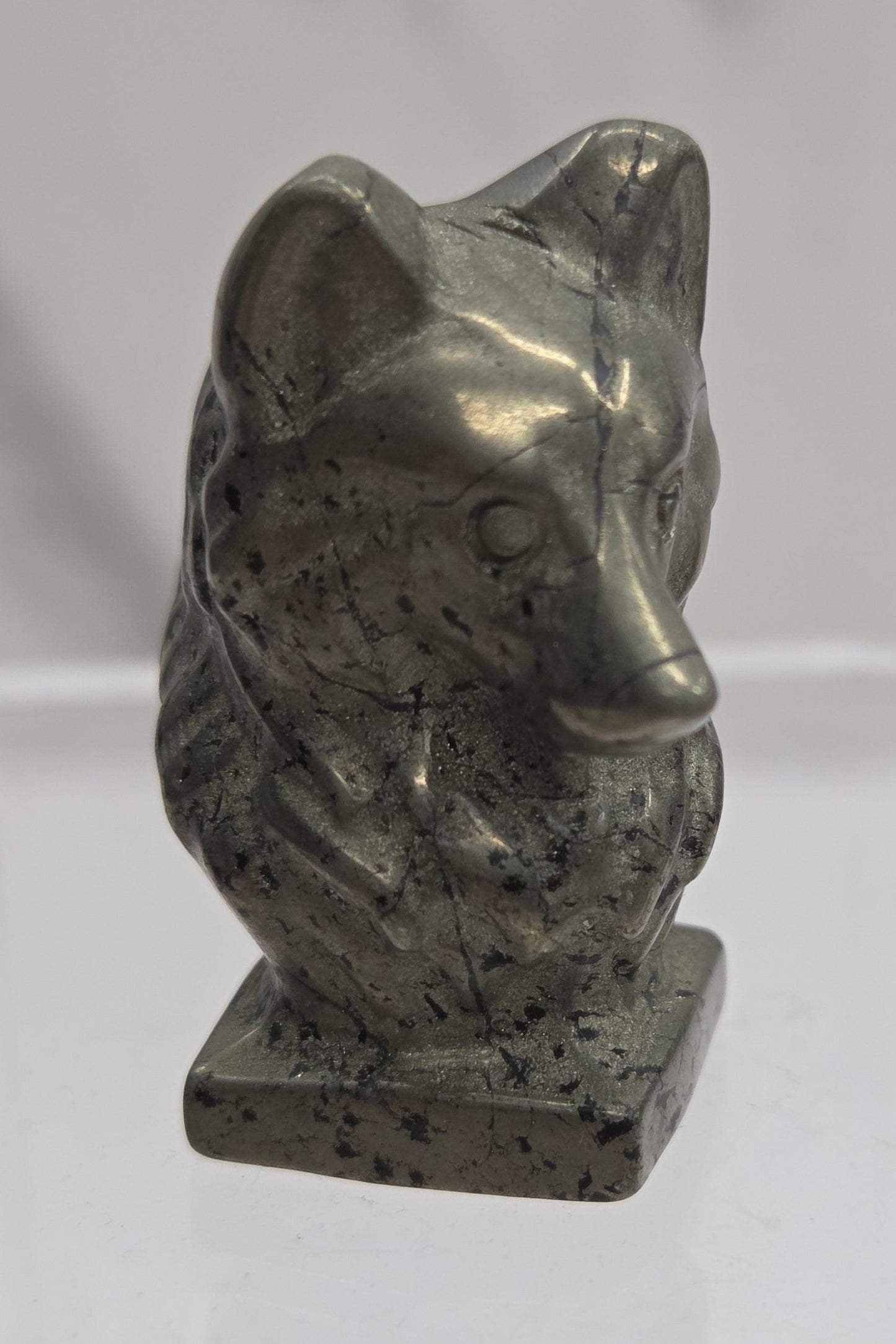 Pyrite carving of a wolf head on a white background