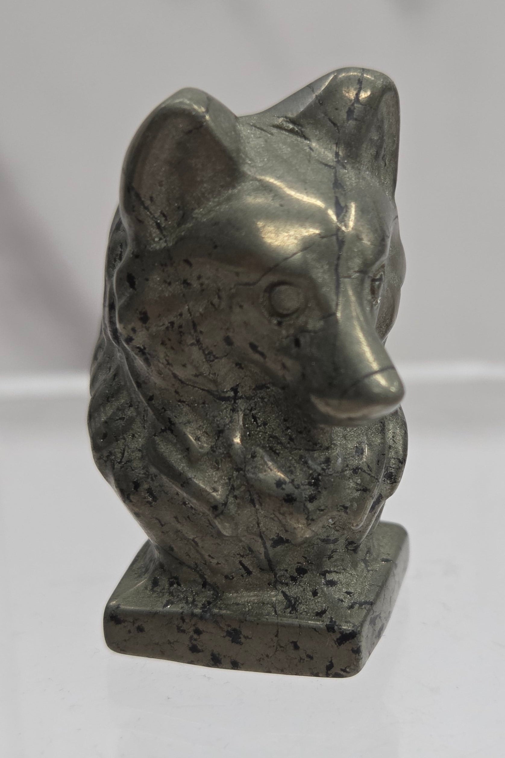 Pyrite carving of a wolf head on a white background