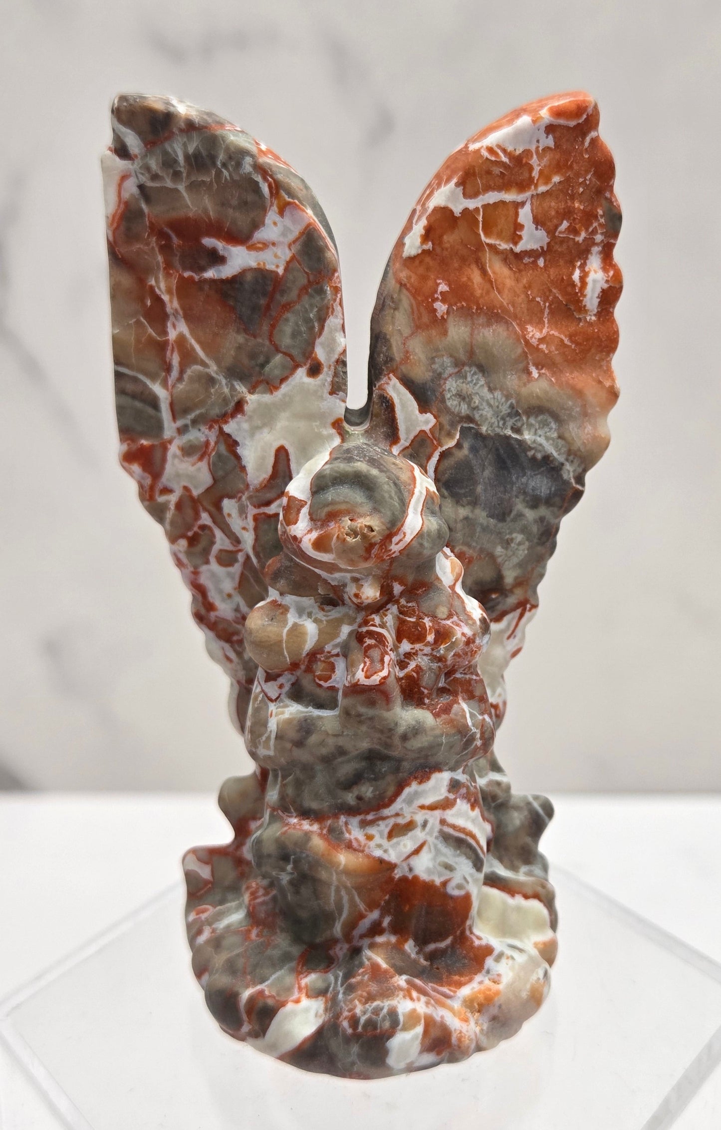 Money Agate praying angel carving on an acrylic stand on a white background
