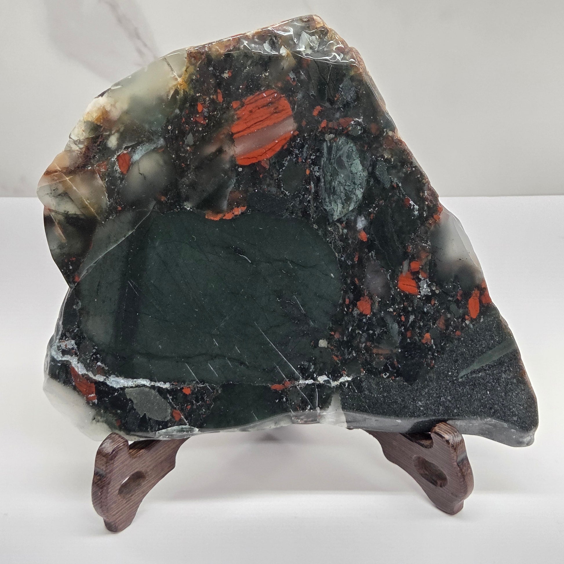 Dark stone African Bloodstone slab with red and gray patterns on a white surface.