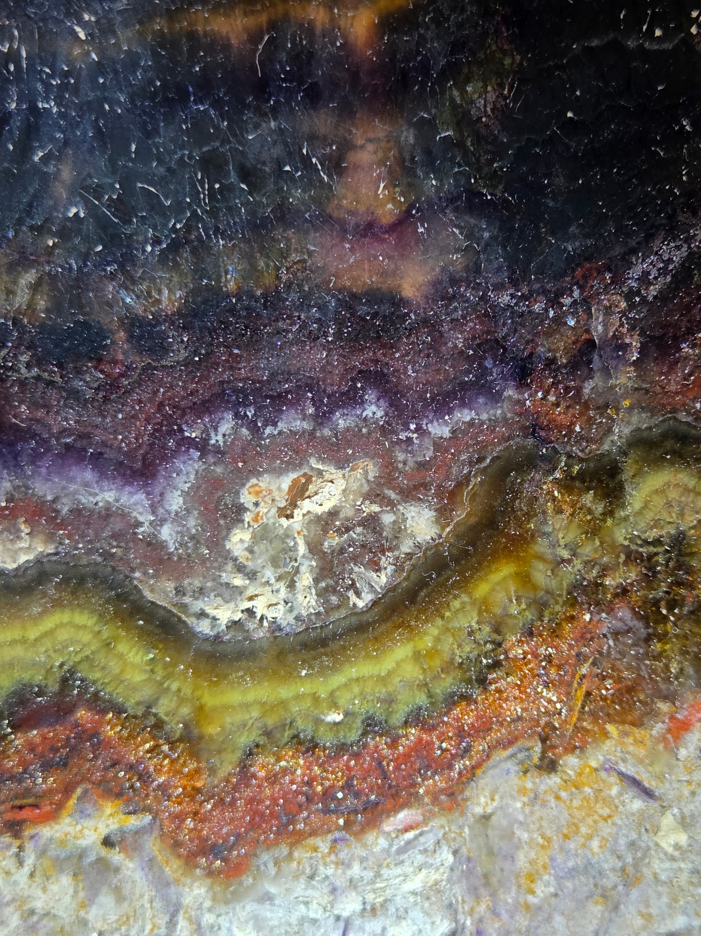 Close-up of a colorful stone with purple, yellow, and brown hues.