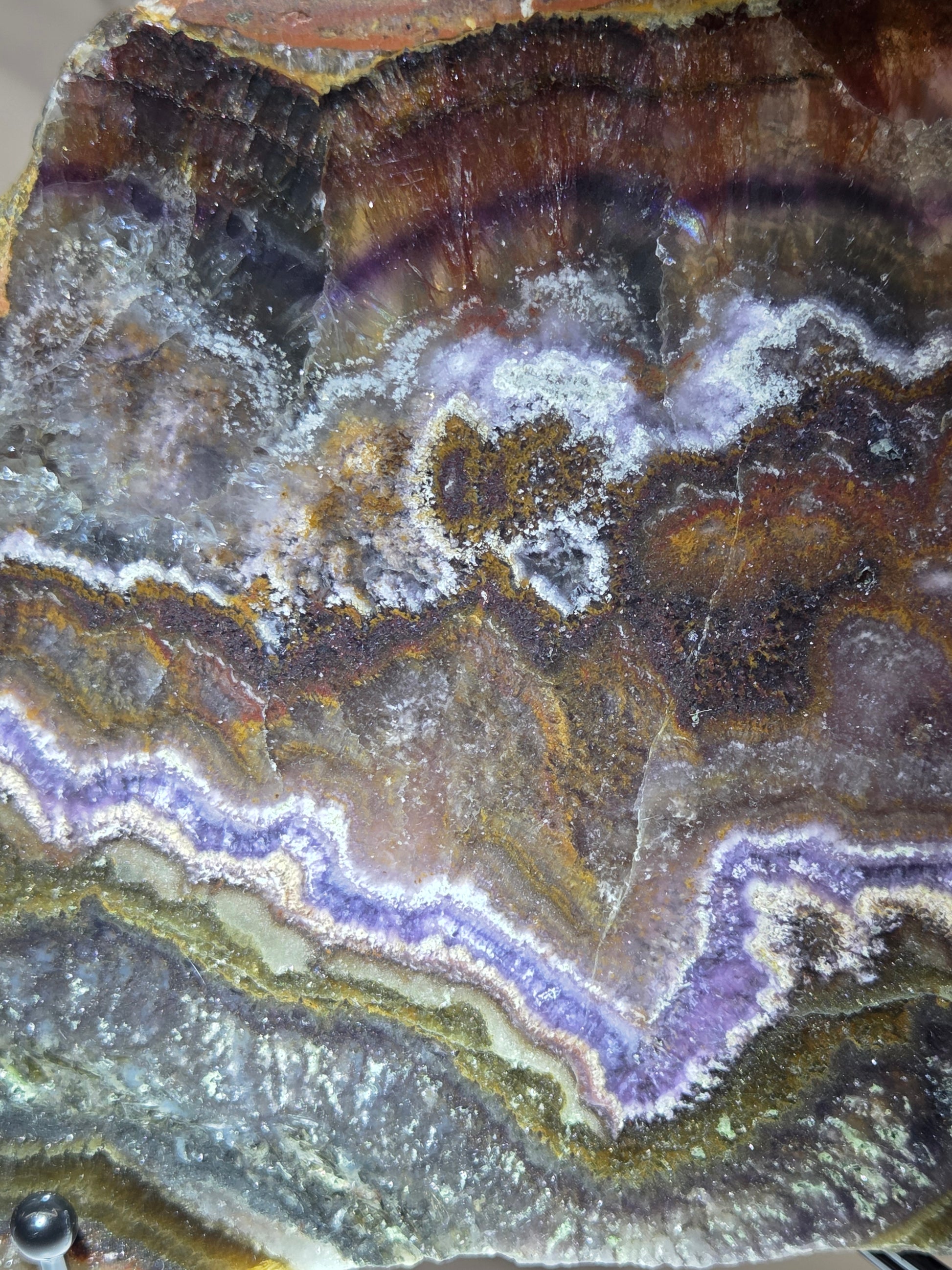 Close-up of a banded crystal slab  with layered purple, brown, and gray patterns