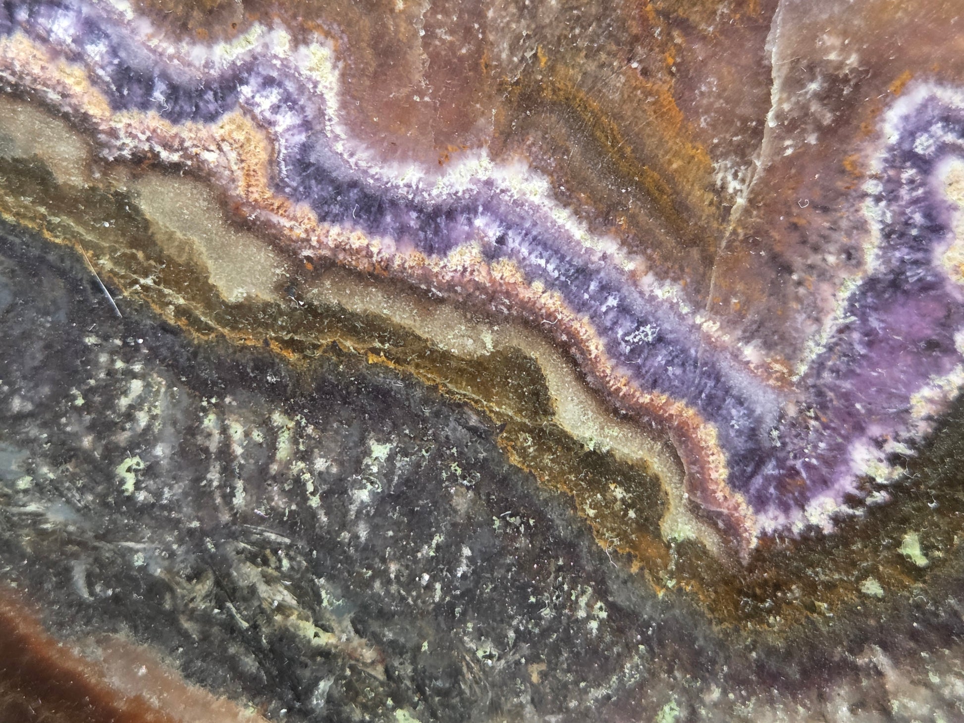 Close-up of a multicolored stone with purple, brown, and gray hues.