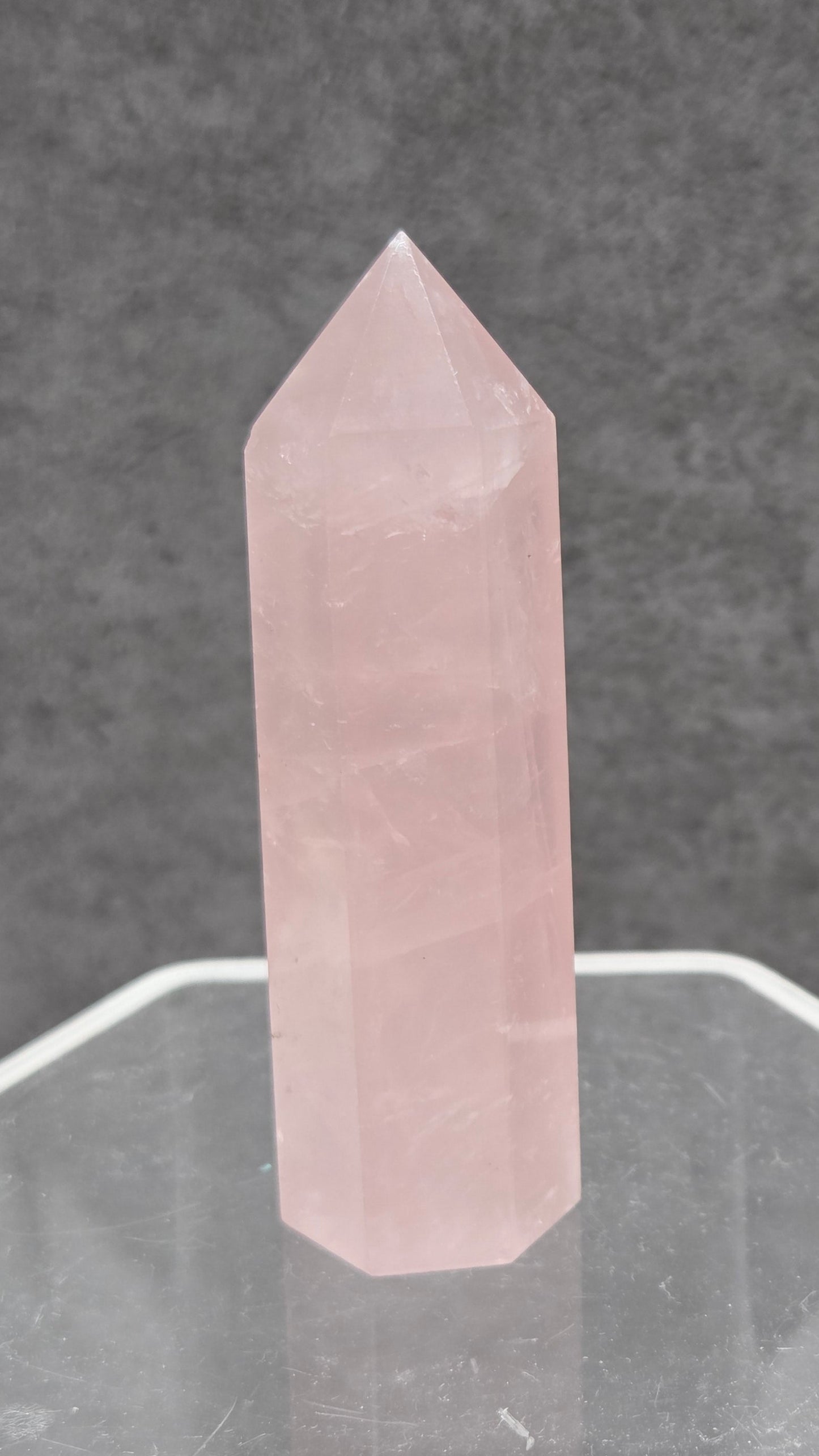 rose quartz crystal point with a gray background