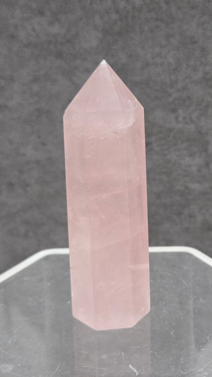 rose quartz crystal point with a gray background
