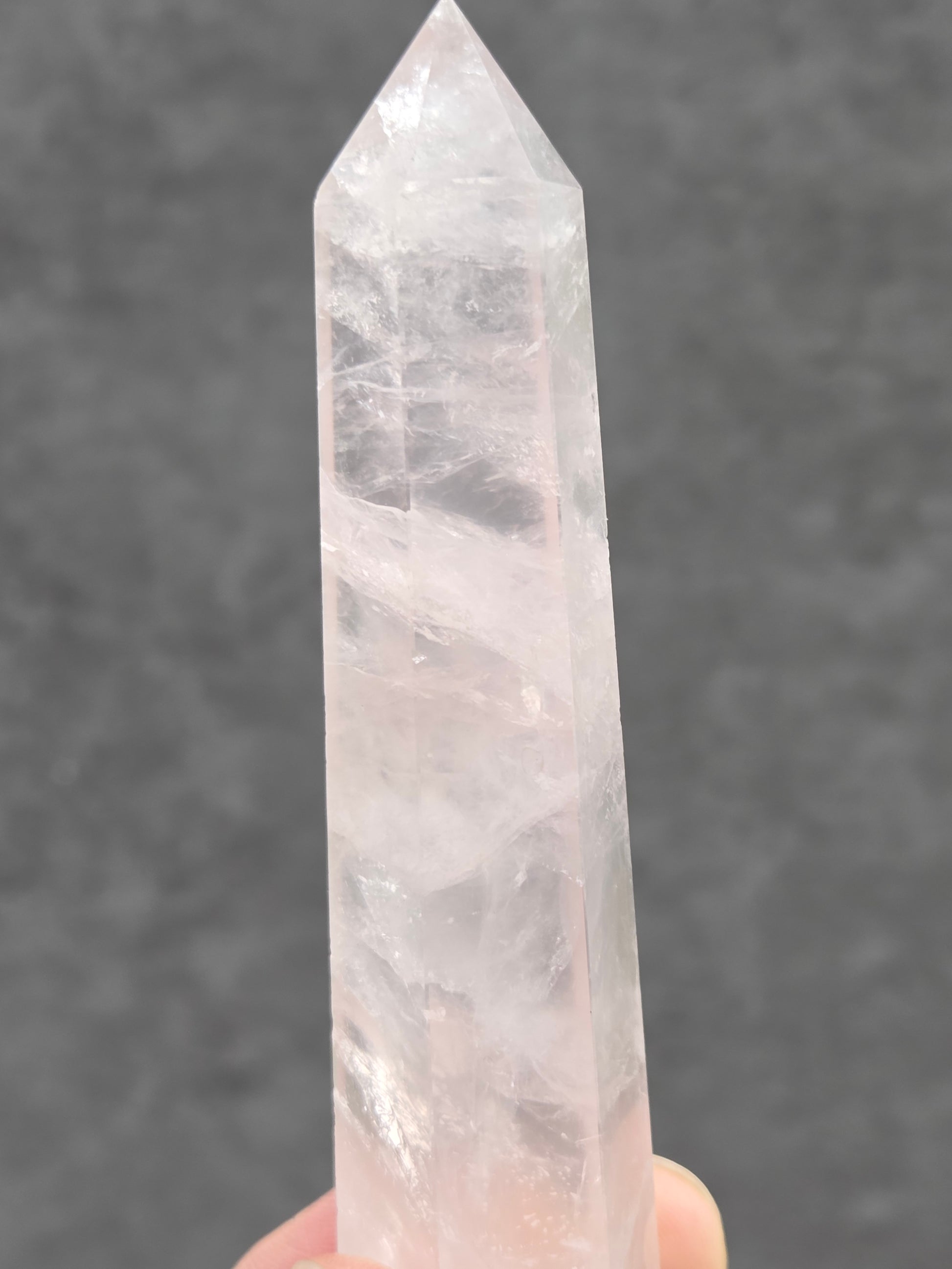 rose quartz crystal point with a gray background